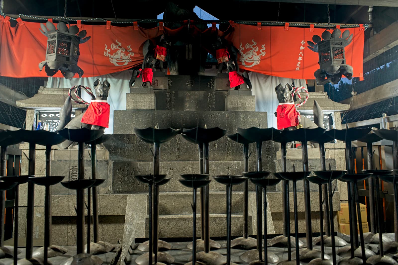 Stone fox statues and a red ceremonial curtain at Fushimi Inari Taisha in Kyoto